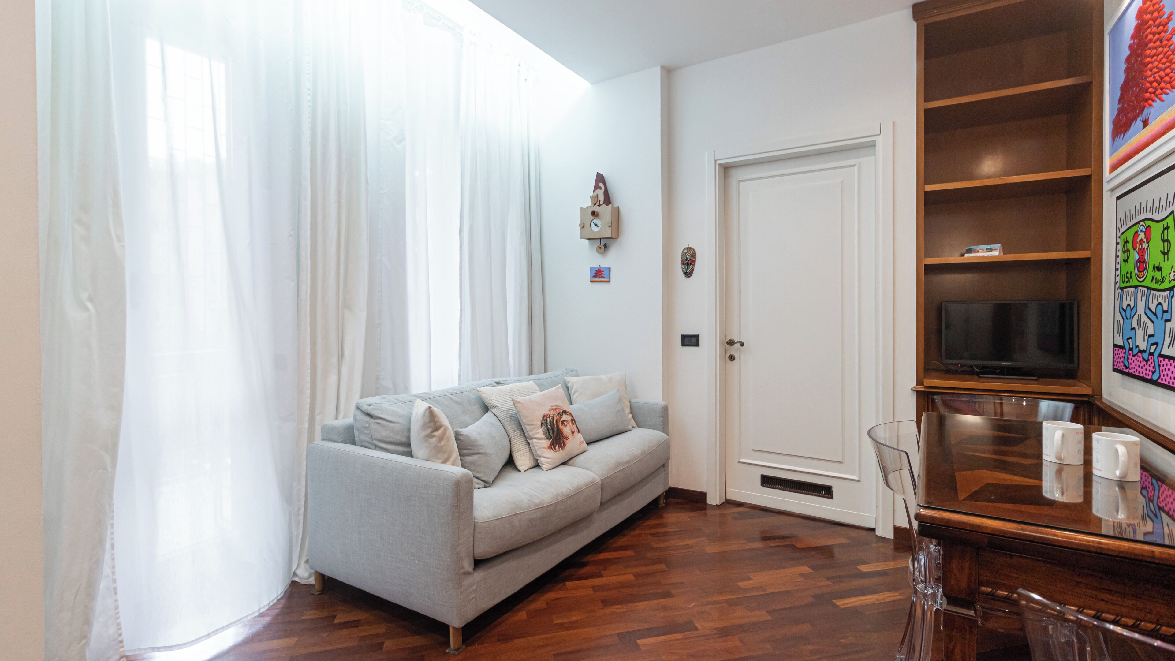 Una sala de estar con sofá, televisor y aparador de madera.