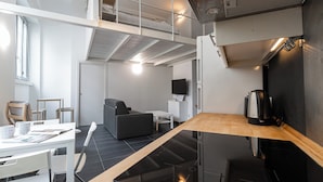 Ein moderner, offener Wohnbereich mit Küchenzeile, Esstisch und einer Sitzecke mit Sofa und Sesseln.