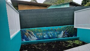 A tiled patio area with a mural of a waterfall and greenery. - Charming 1-bedroom apartment with WiFi, AC, swimming pool, in lovely Soufrière (St lucia)