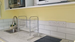 A kitchen with a microwave, toaster, sink, and a kettle. - Charming 1-bedroom apartment with WiFi, AC, swimming pool, in lovely Soufrière (St lucia)