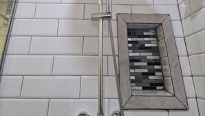 A shower with a chrome head, a handheld showerhead, and a wall-mounted control panel. - Charming 1-bedroom apartment with WiFi, AC, swimming pool, in lovely Soufrière (St lucia)