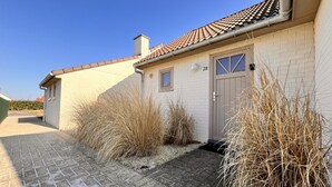 Ein bungalow mit einem Ziegeldach, einer Haustür und einem kleinen Fenster.