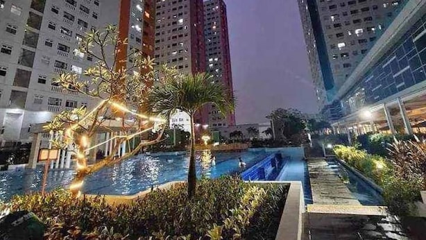 A residential building complex with multiple high-rise apartments, a swimming pool, and well-maintained landscaping. - Expansive dual-room  for the ultimate family getaway Offering a garden, (Daerah Khusus Ibukota Jakarta)