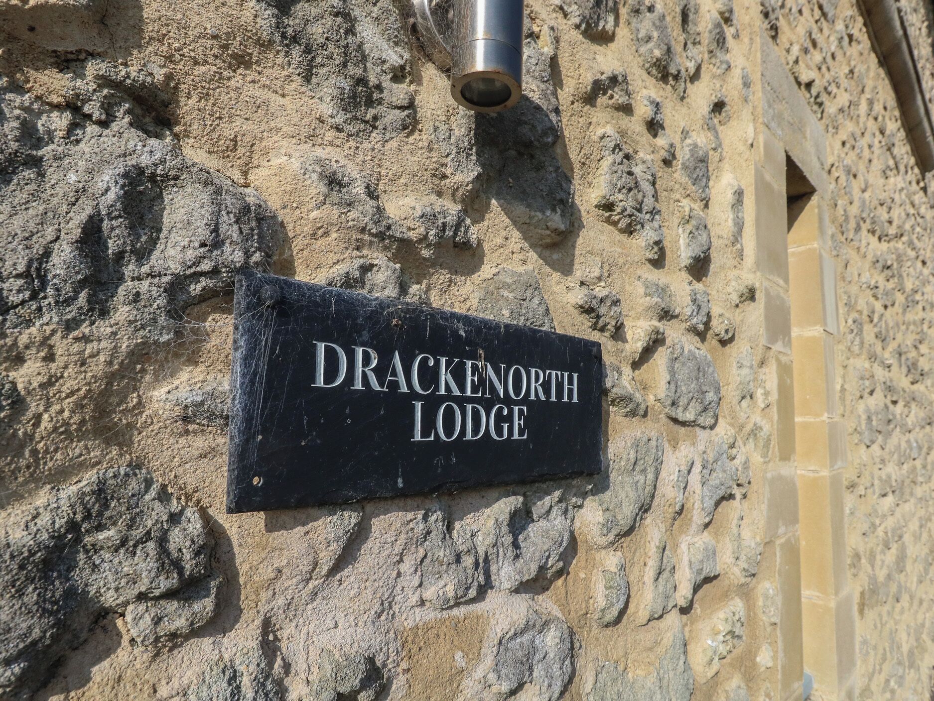 A sign reading "DRACKENORTH LODGE" mounted on a stone wall.