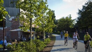 A paved pathway with cyclists, a brick building, and greenery. - Historic Cabbagetown by  Stadium, walk to Eastside BeltLine, Krog St. Market (Atlanta)