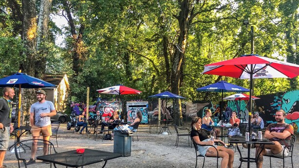 An outdoor seating area with tables and chairs under umbrellas, surrounded by trees. - Historic Cabbagetown by  Stadium, walk to Eastside BeltLine, Krog St. Market (Atlanta)