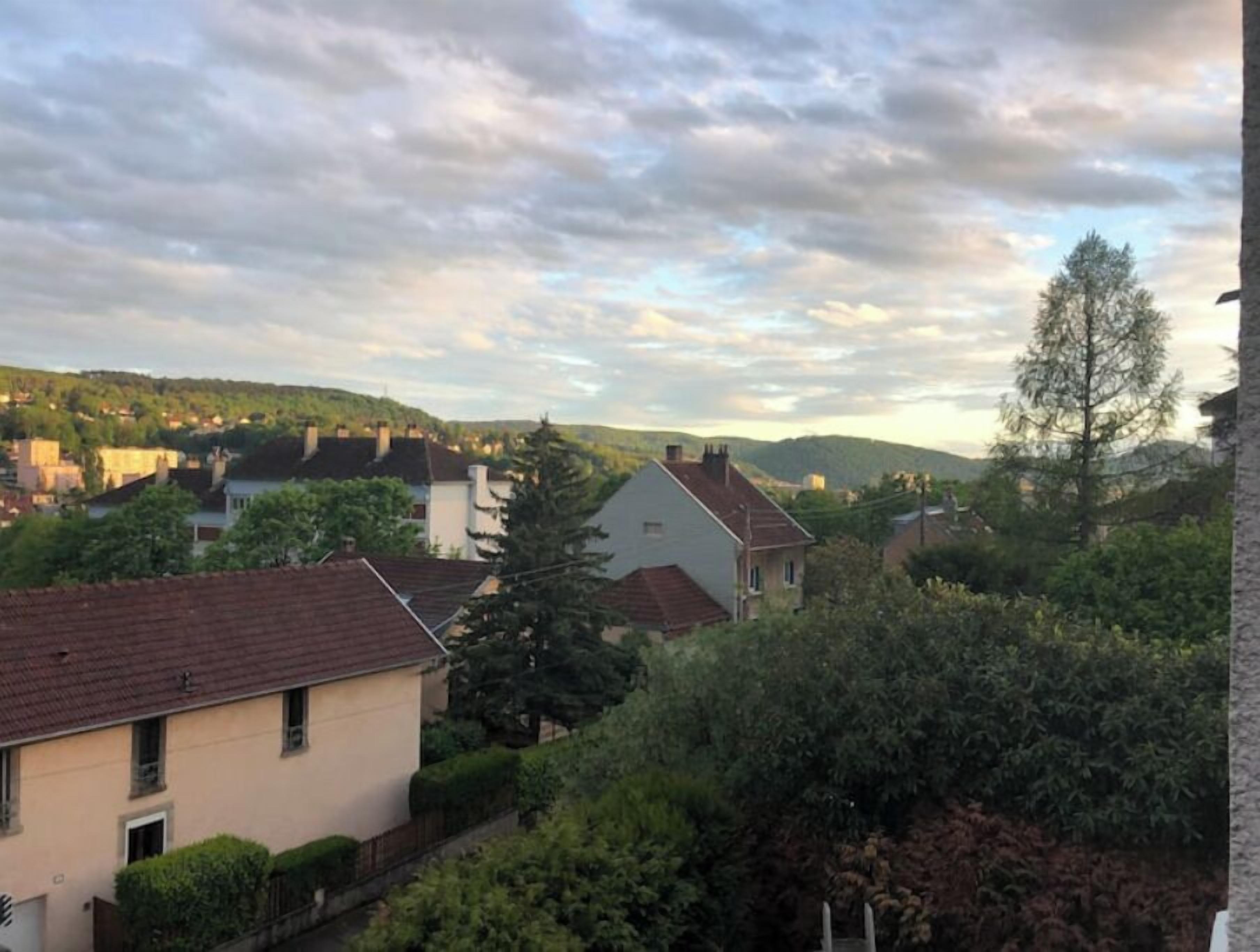 Zona residencial com casas, árvores e uma paisagem montanhosa ao fundo.