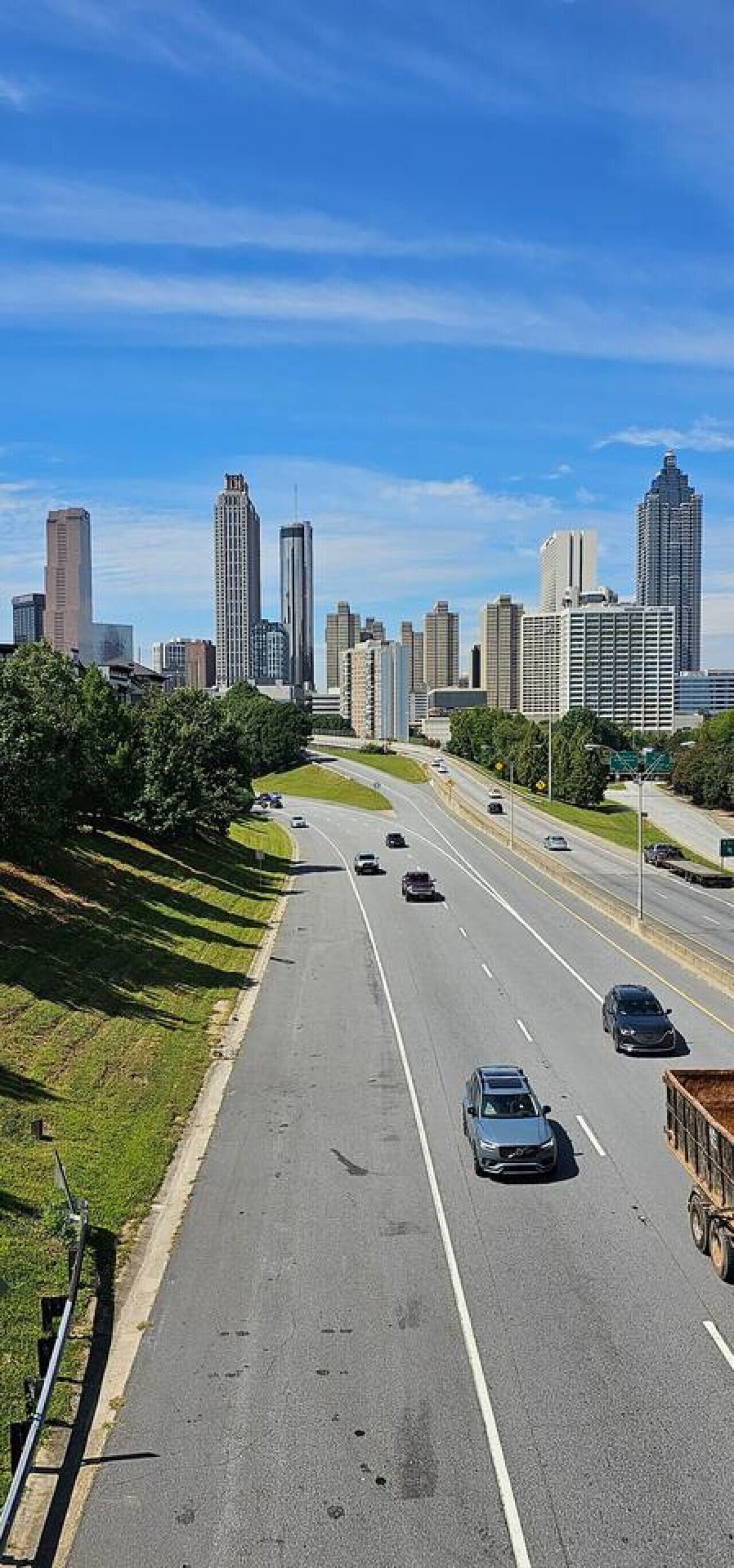 Una autopista con varios carriles, con vehículos, rodeada de edificios urbanos y vegetación.