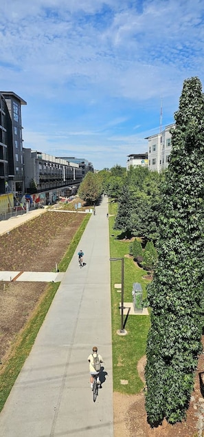 A pathway with cyclists, surrounded by greenery and modern buildings.