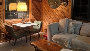 A cozy room with a wooden ceiling, a ceiling fan, a dining table with chairs, a sofa, and a coffee table. - Rustic Retreat in Charming Leavenworth- Wifi and W/D! (Leavenworth)