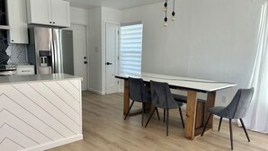 Une cuisine moderne avec des meubles blancs, un réfrigérateur en acier inoxydable et un four encastré.