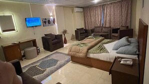 Una camera d'albergo con un letto, una scrivania, una sedia, una televisione e una finestra con tende.