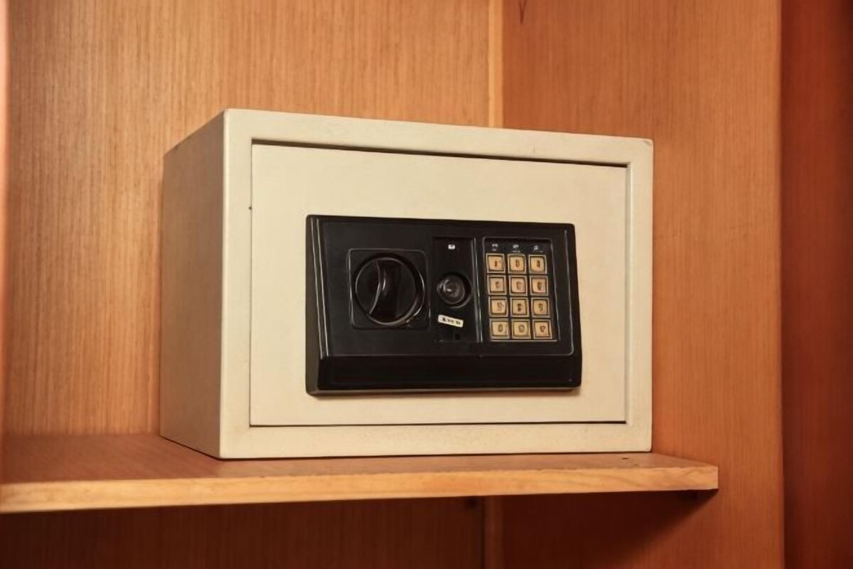 A safe deposit box with a combination dial and keypad, placed on a wooden shelf.