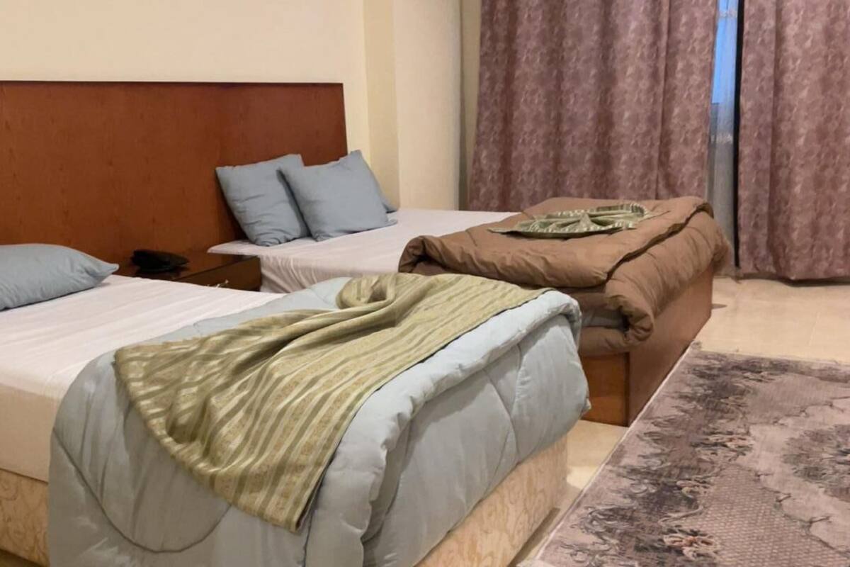 A hotel room with two beds, each with a different style of headboard and bedding.