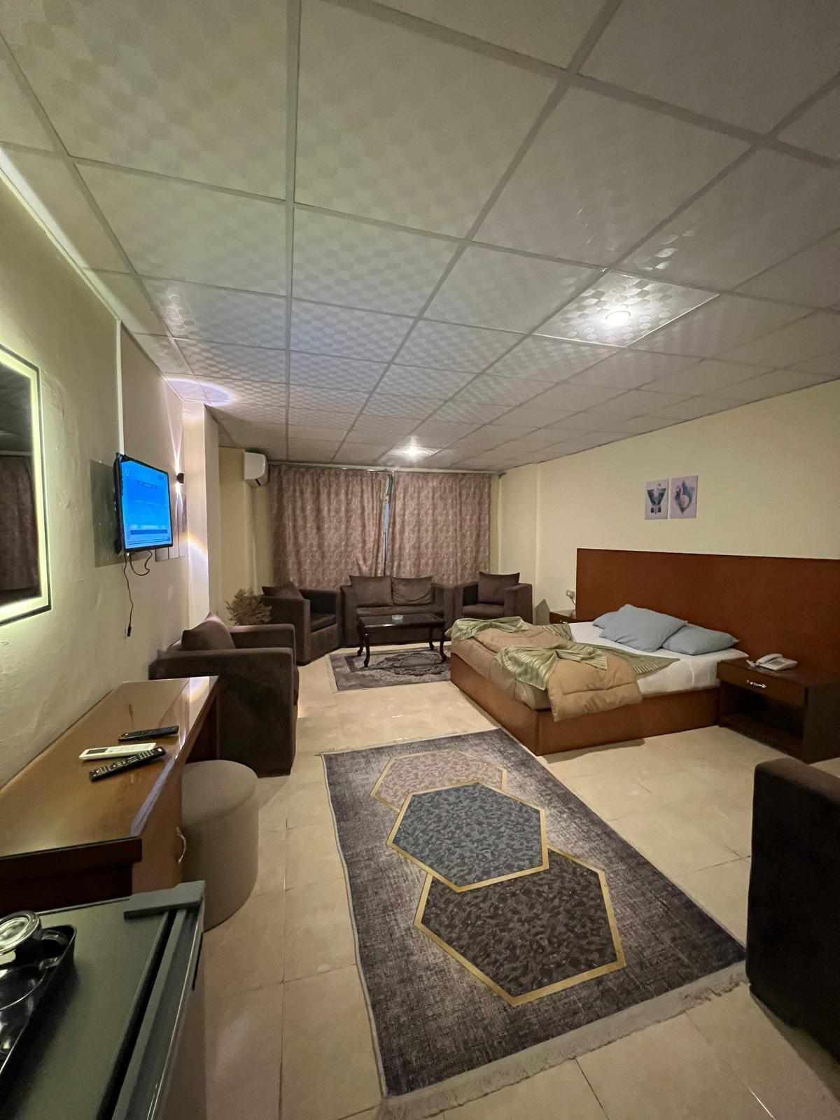 Habitación de hotel con una cama, un escritorio con computadora, televisor y sofá.