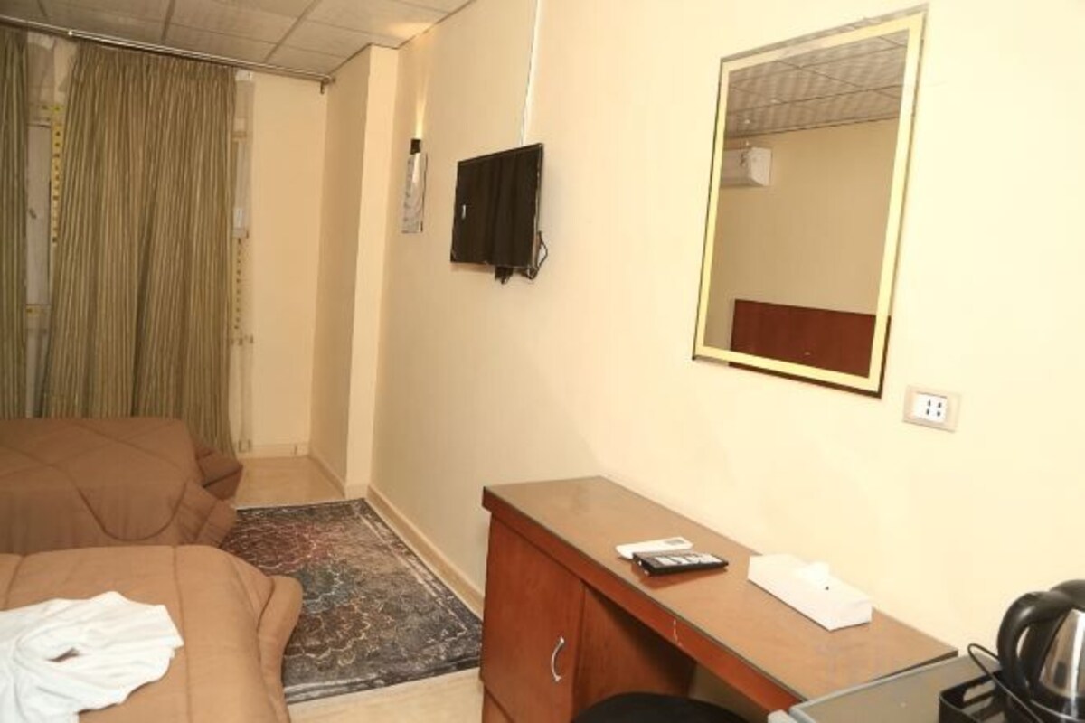 A hotel room with a bed, a desk, a mirror, and a television.