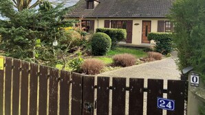 A two-story house with a tiled roof, a front porch, and a well-maintained garden with various shrubs and a small tree. - House of Peace and Nature (Charencey)
