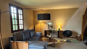 A cozy living room with a sofa, a coffee table, a lamp, and a bookshelf. - House of Peace and Nature (Charencey)