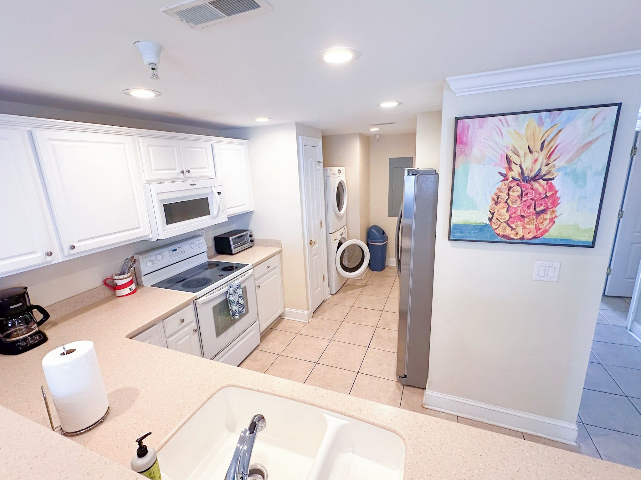 A modern kitchen with white cabinets, a microwave, stove, oven, and a sink.