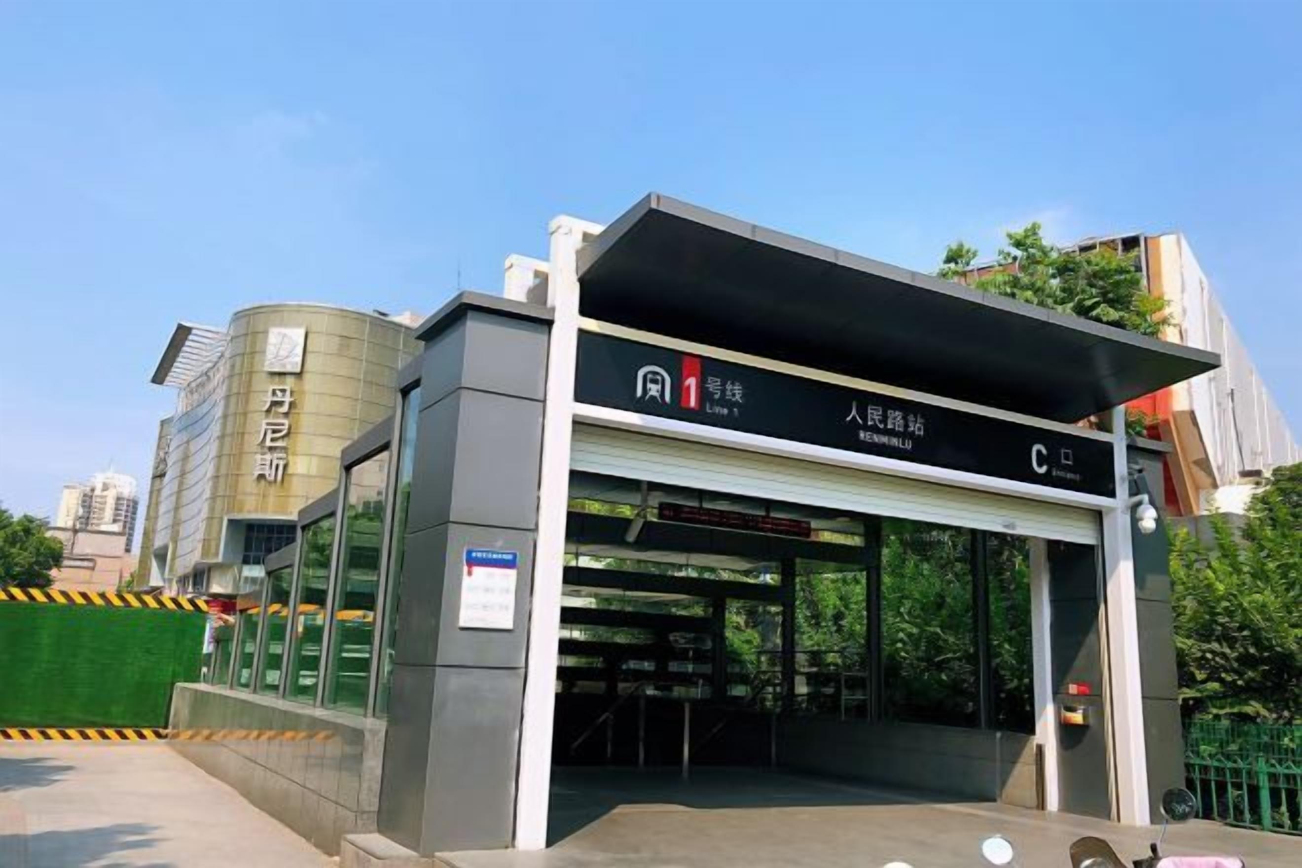 A modern building with a covered entrance, signage indicating a public facility, and a clear sky in the background.