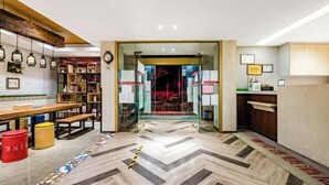 Un espace d’accueil doté d’un comptoir de réception en bois, d’une cloison en verre et d’un sol à motifs en chevrons.