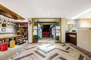 A reception area with a wooden reception desk, a glass partition, and a chevron-patterned floor.