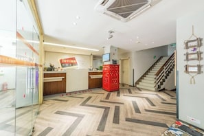 A reception area with a chevron-patterned floor, a reception desk, a staircase, and a wall-mounted television.