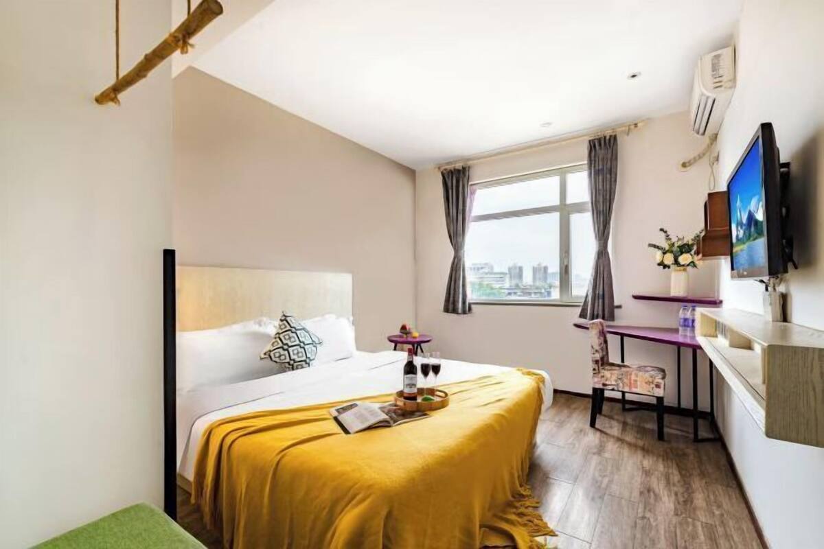 Une chambre d’hôtel avec un lit, un bureau, une télévision et une fenêtre avec des rideaux.