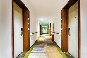 Un couloir d’hôtel avec les portes numérotées 415 et 418, une moquette à motifs et une poubelle.