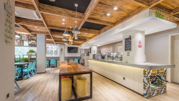 Un intérieur moderne avec un plafond en bois, un îlot central doté d’un comptoir et des espaces salon.
