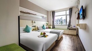 Une chambre d’hôtel avec deux lits, une télévision, une fenêtre donnant sur la ville et un bureau avec une chaise.