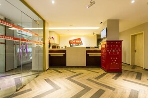 Un espace d’accueil comprenant un comptoir de réception, un téléviseur et un distributeur automatique rouge.