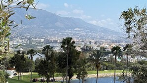 Campo de golf con vistas a una ciudad y una montaña al fondo.