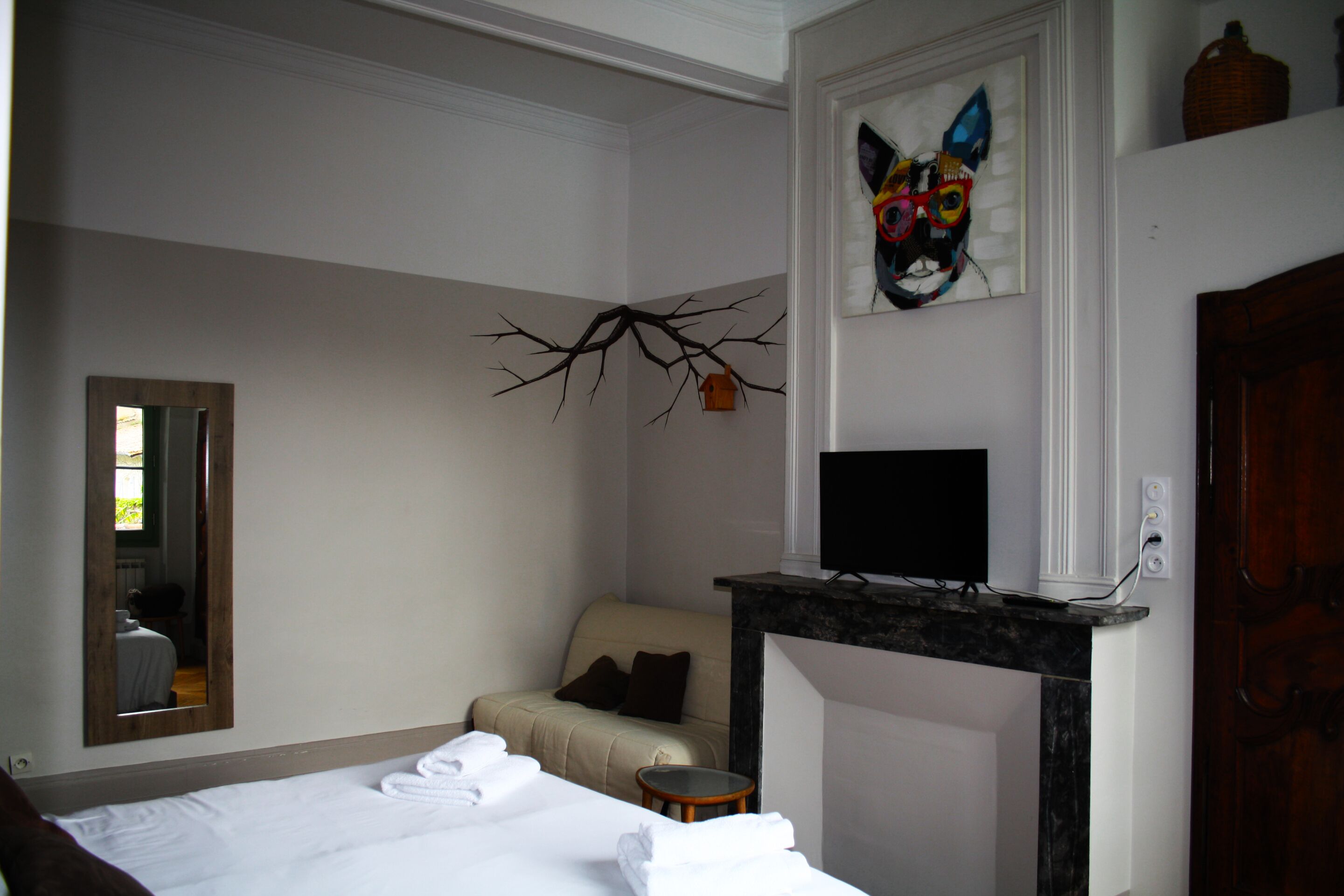 Una camera d'albergo con un letto, un divano, un tavolino rotondo, una TV e un camino.