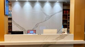 Un comptoir d’accueil au design en marbre, doté d’un écran numérique et d’une enseigne.
