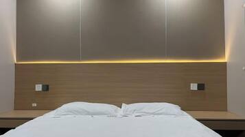 Habitación de hotel con cama, cabecera de madera y dos interruptores de luz en la pared.