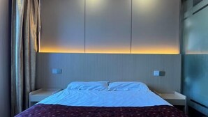 Une chambre d’hôtel avec un lit, des tables de chevet et une lampe fixée au mur.