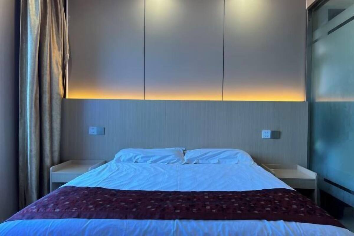 Una camera d'albergo con un letto, comodini e una lampada a parete.