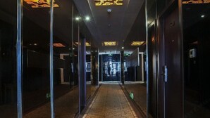 Un couloir doté de portes en verre, d’un tapis à motifs et d’un plafond agrémenté d’un éclairage décoratif.
