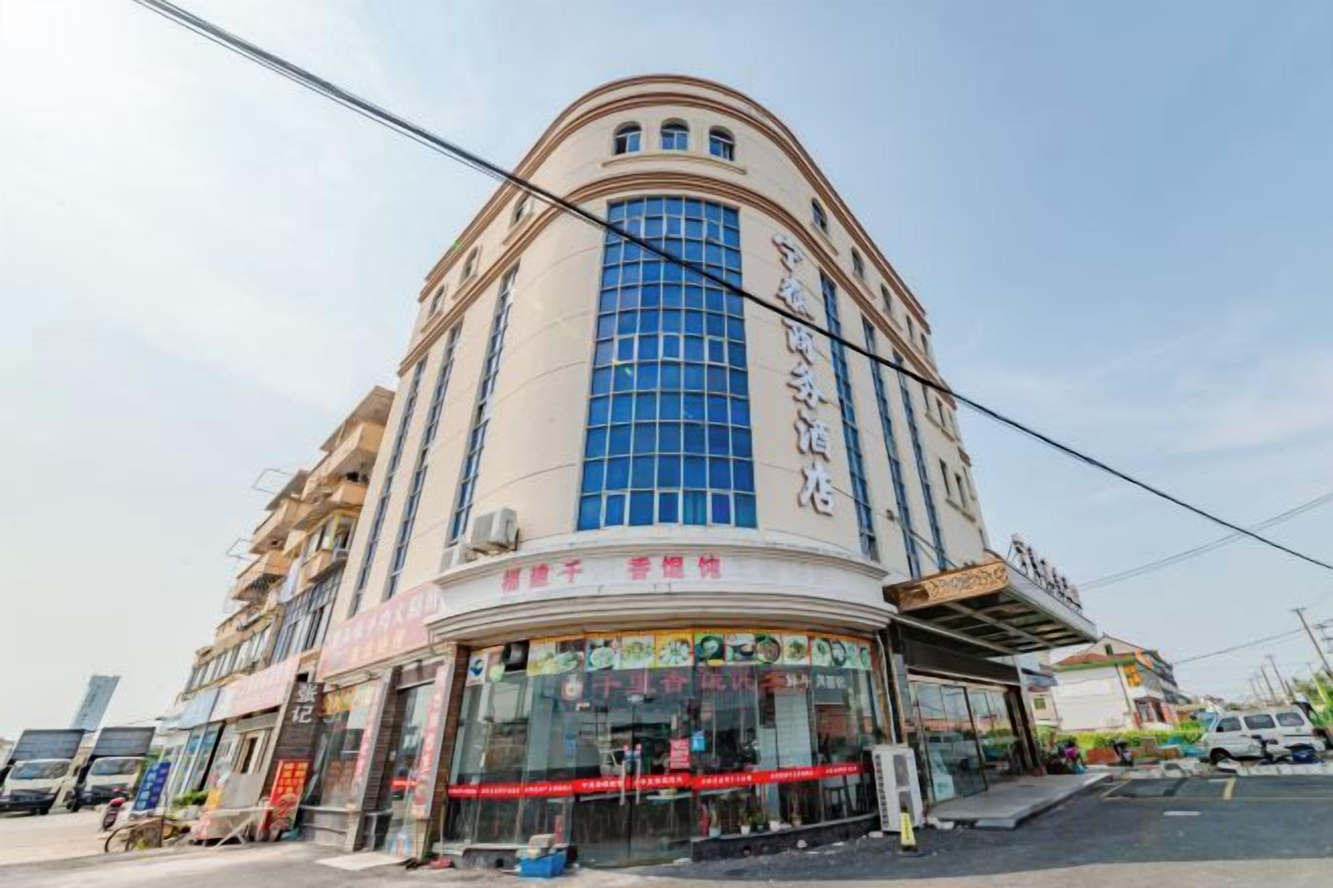 Un hotel de varios pisos con fachada curva, amplias ventanas y entrada a nivel de calle con puerta de vidrio.