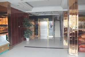A hotel lobby with a staircase, a potted plant, and a seating area. - Ningtai Business Hotel (Shanghai)