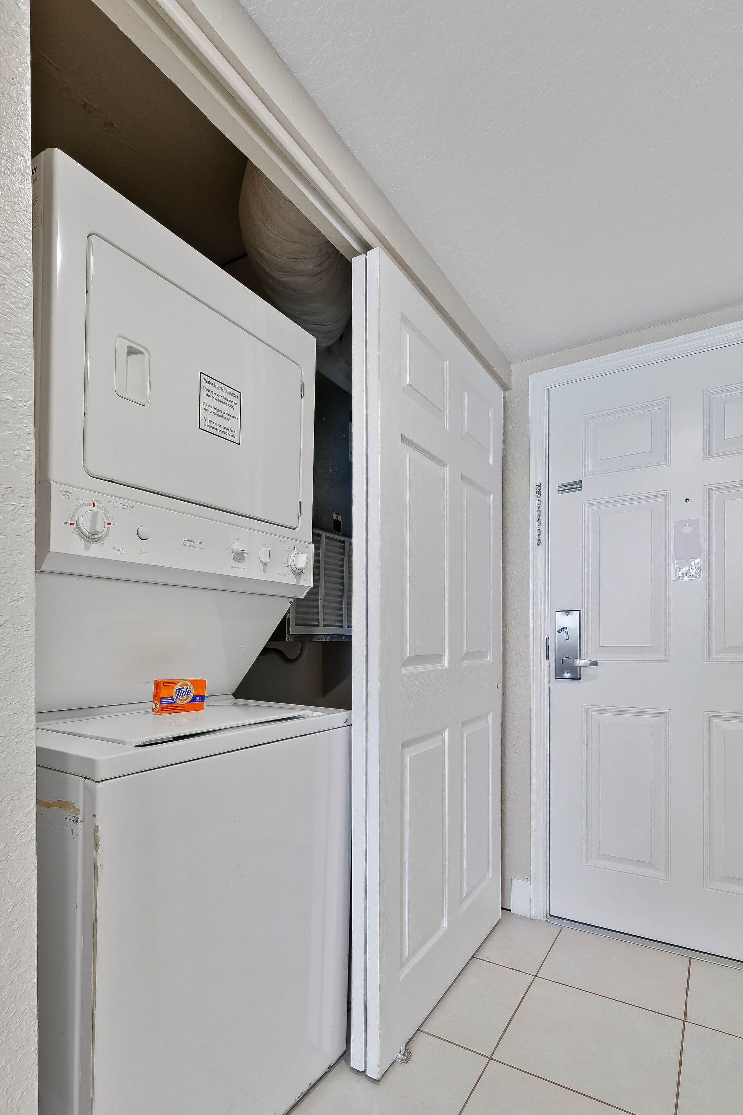 A laundry room with a washer, dryer, and a door to a closet.
