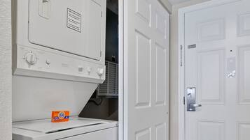A laundry room with a washer, dryer, and a door to a closet.