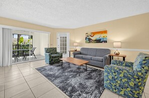 A living room with a sofa, armchairs, a coffee table, and a painting on the wall. - Spacious 2BR Villa Near Disney (Kissimmee)