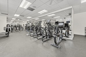 A gym with various exercise machines, a sauna, and a mirrored wall. - Spacious 2BR Villa Near Disney (Kissimmee)