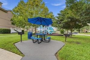 Shaded picnic area with tables set among green surroundings and play equipment nearby - Spacious 2BR Villa Near Disney (Kissimmee)