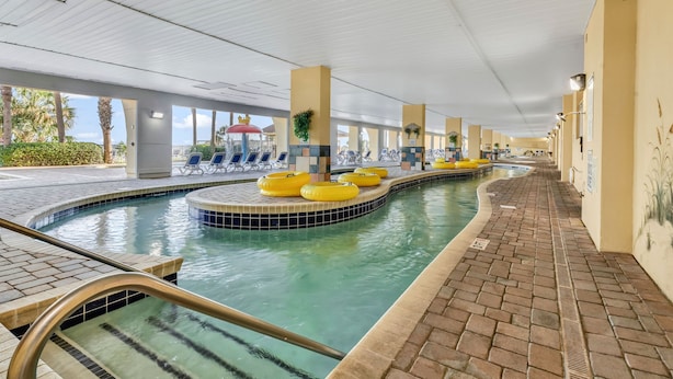 A pool area with yellow floating rings, lounge chairs, and a tiled walkway.