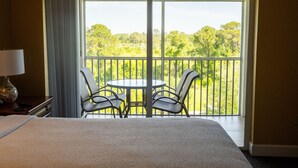 A hotel room with a bed, a table with chairs, and a balcony with a view of trees. - Spacious 2BR Condo near Disney (Kissimmee)