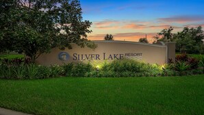 A sign for Silver Lake Resort with a logo, surrounded by well-maintained grass and plants. - Spacious 2BR Condo near Disney (Kissimmee)