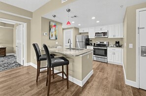 A modern kitchen with a central island, stainless steel appliances, and white cabinetry.